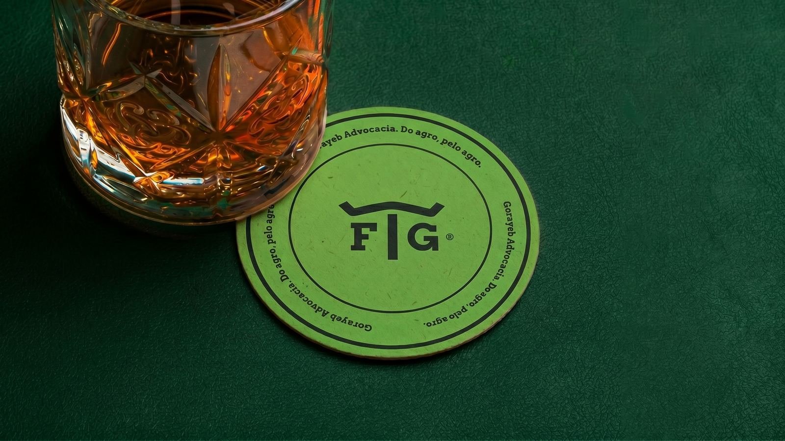 Porta-copos verde com o FTG e um copo de whisky